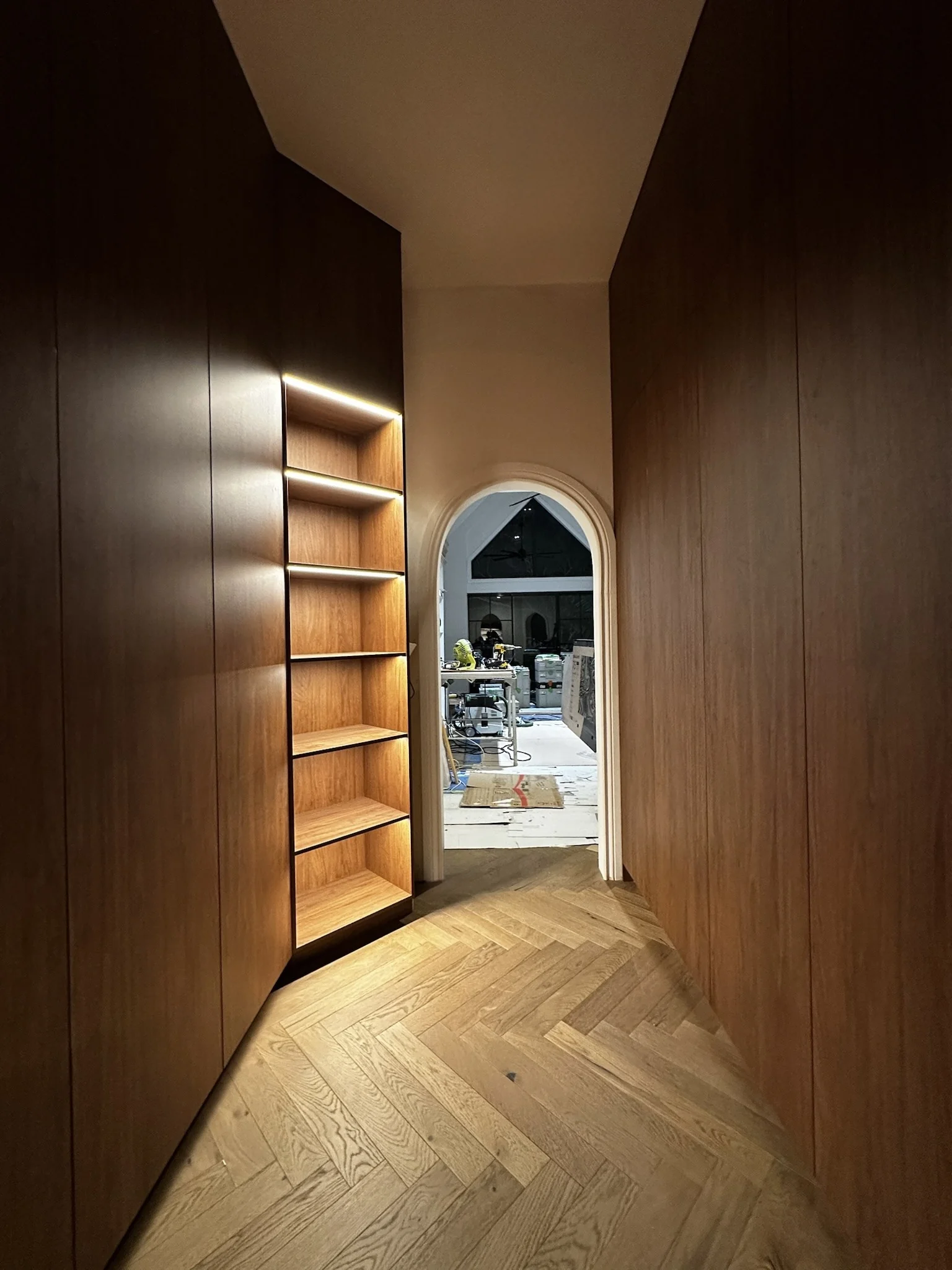 Walnut wardrobe corridor with backlit open shelving during installation