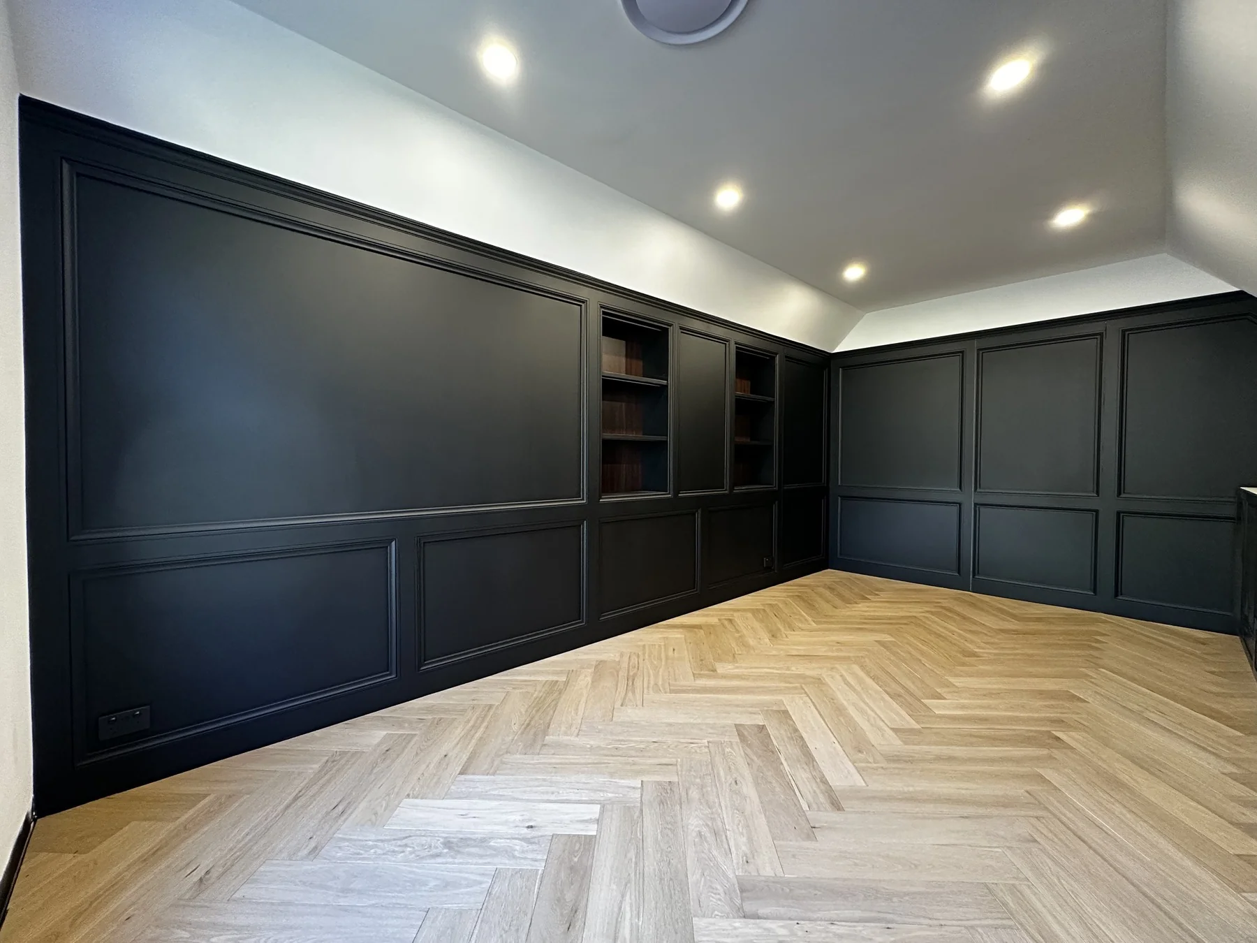 Matte black built-in cabinetry with open shelving and herringbone timber flooring