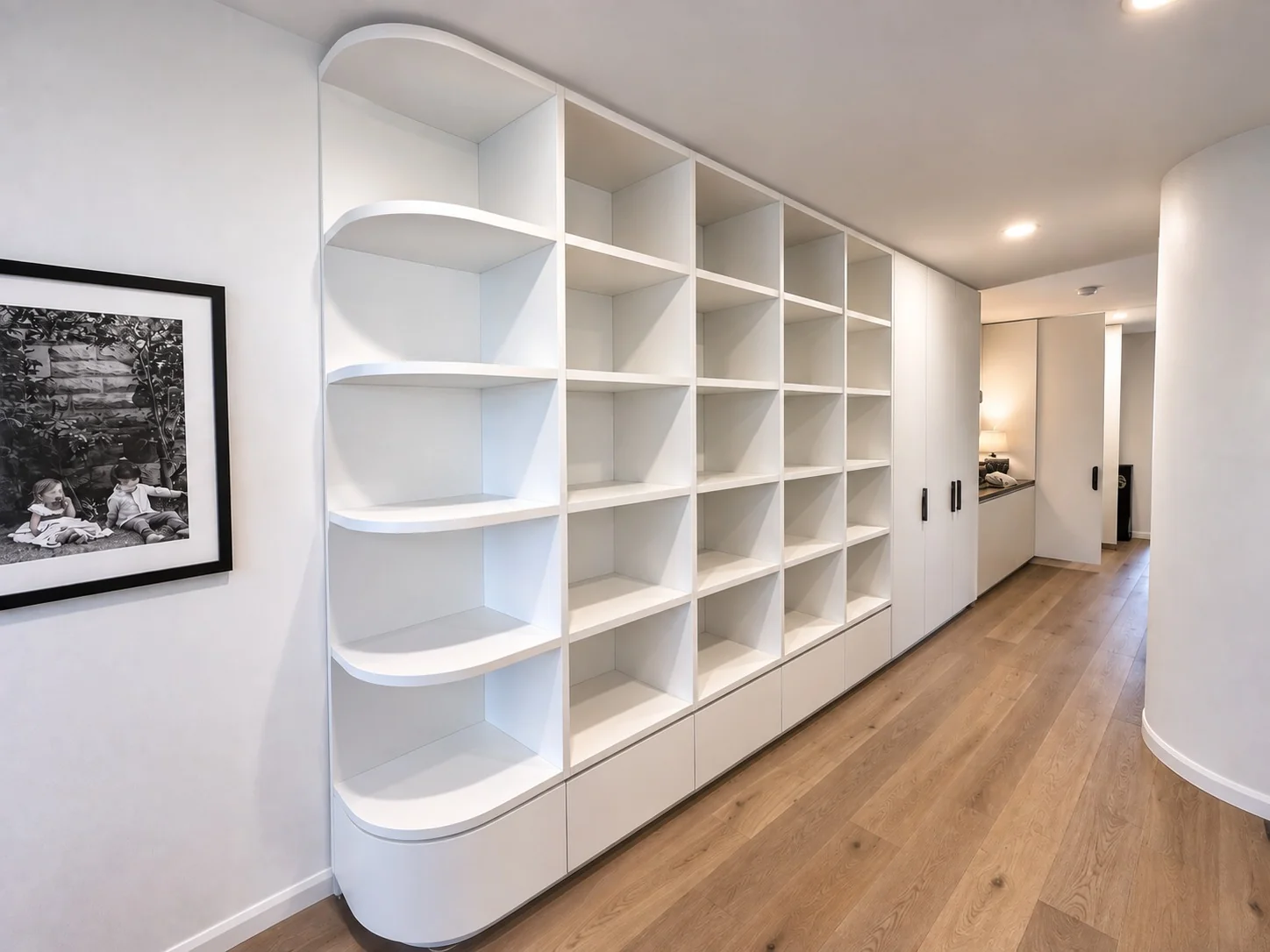 Floor-to-ceiling white display shelving with curved corner cabinetry