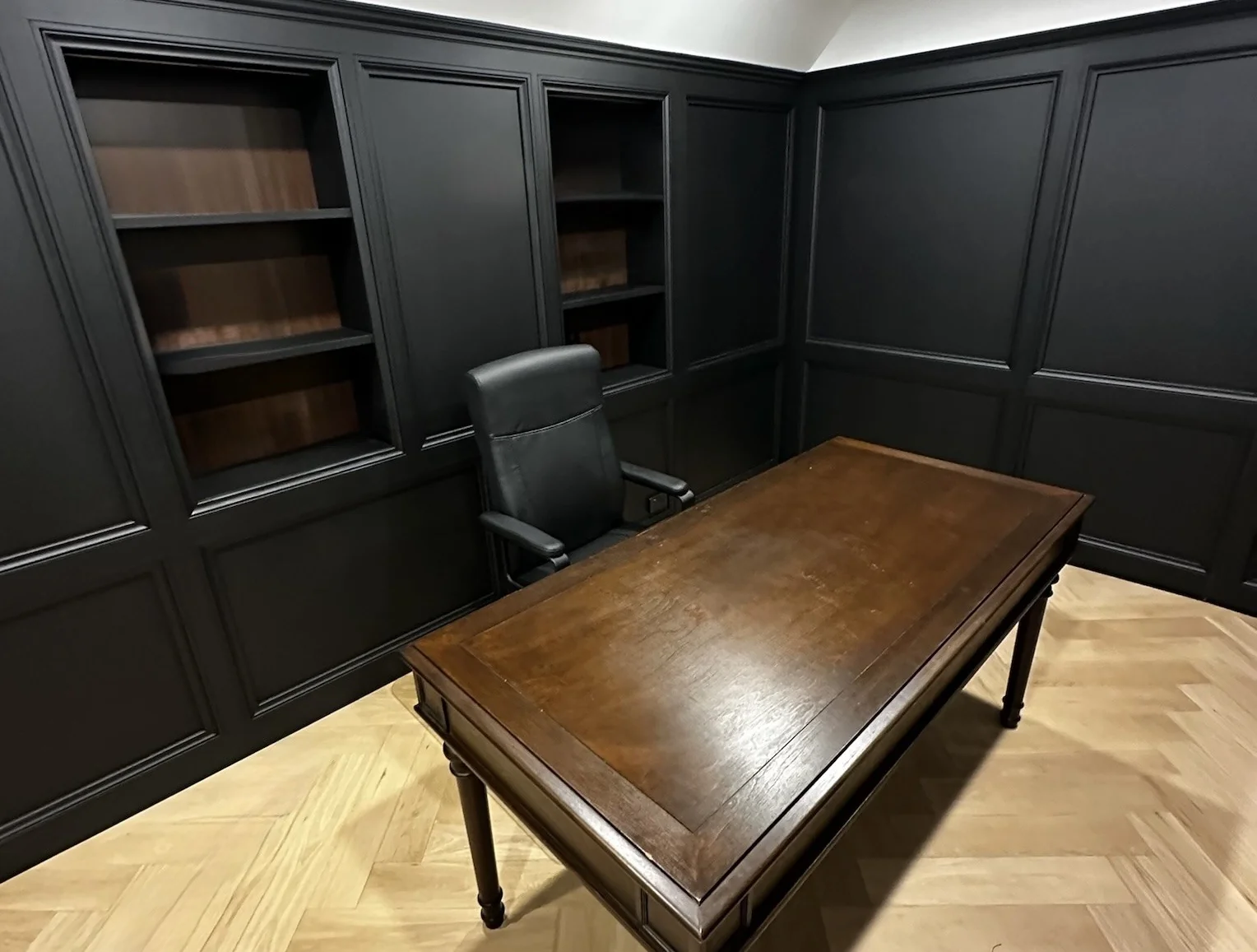 Matte black panelled home office with built-in shelving and timber desk