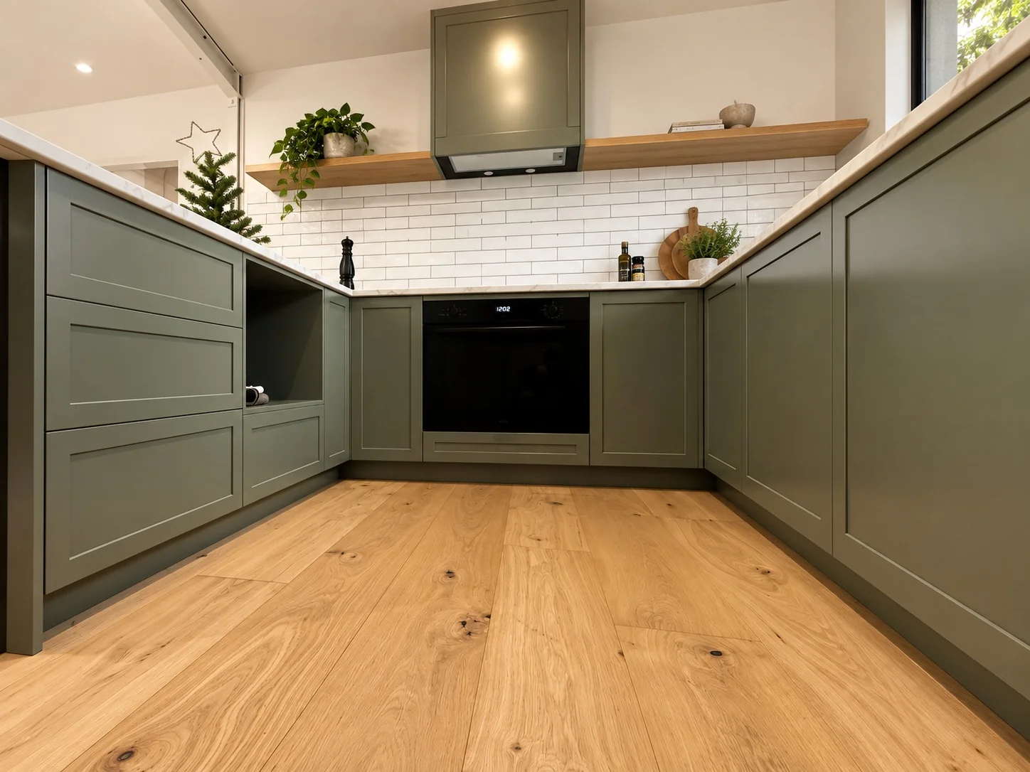 Sage green shaker kitchen joinery with oak flooring