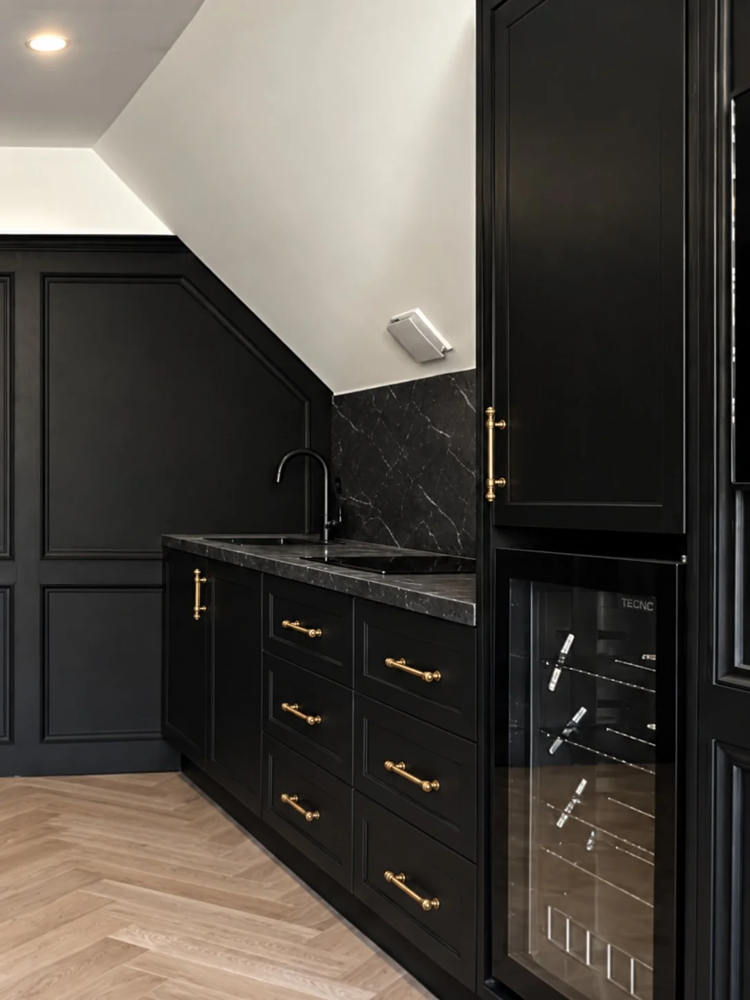 Black kitchen wet bar joinery with brass hardware and wine fridge